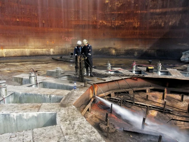 RGL ultra high pressure water jetting team performing spark-free abrasive cutting on petrochemical storage tank in refinery